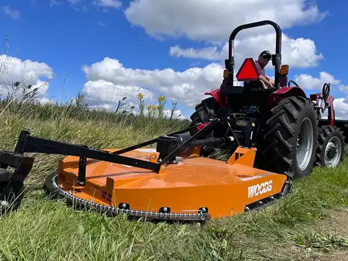 Man on tractor with Woods rotary cutter mowing weeds in a pasture