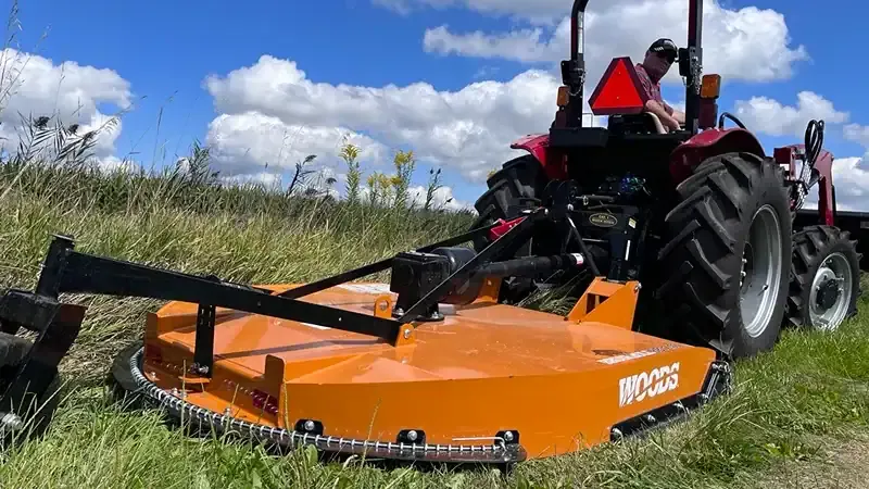 man on tractor mowing with woods rotary cutter