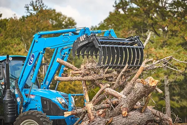 LS tractor lifting a pile of logs with a loader grapple