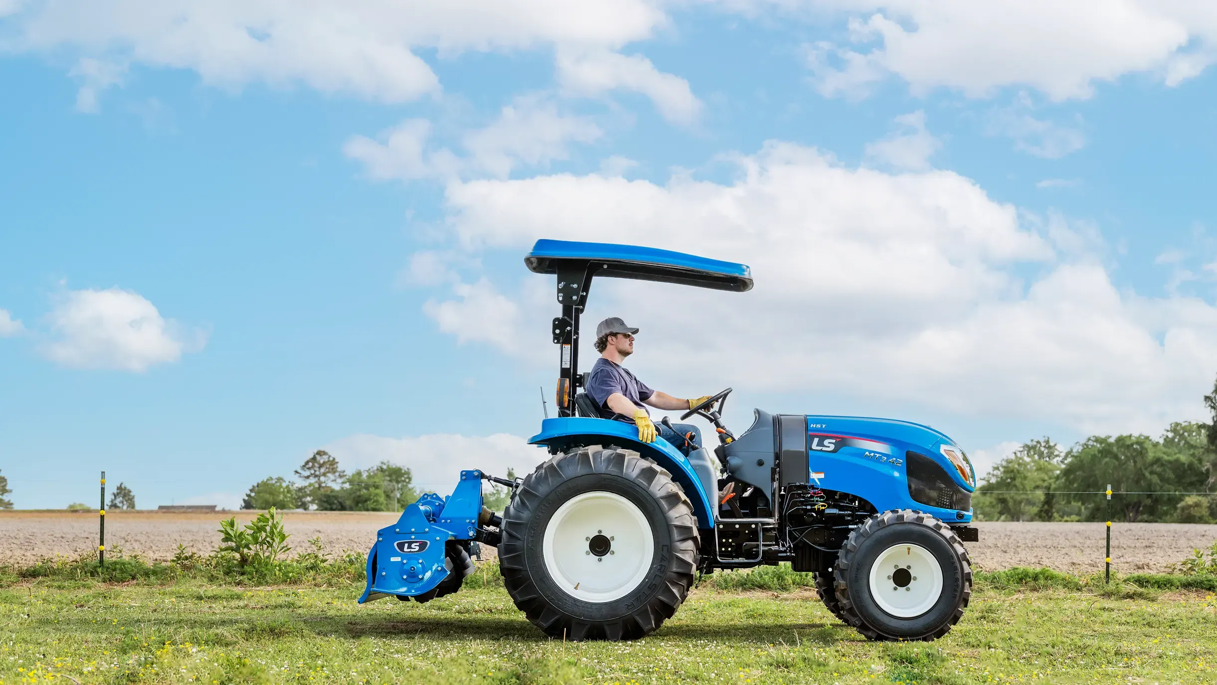 LS compact tractor tilling a field